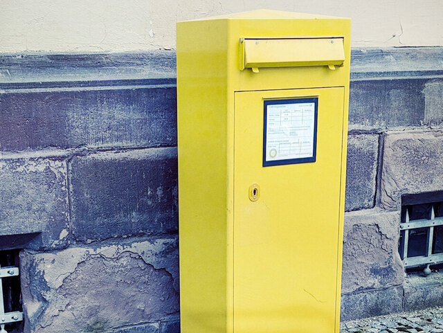 gelber Briefkasten an einer Mauer