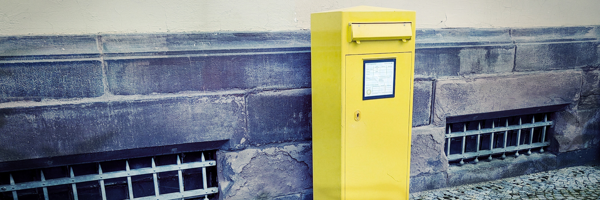 gelber Briefkasten an einer Mauer